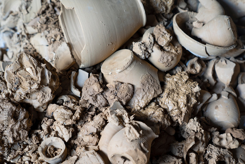 Broken undried clay pottery and pots lining the ground with mug in a pottery factory. photo