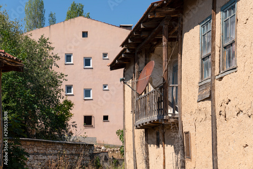 Abandoned soil house with old rusty satellite dish. Old rusty satellite TV dish attached to the wall of the old house