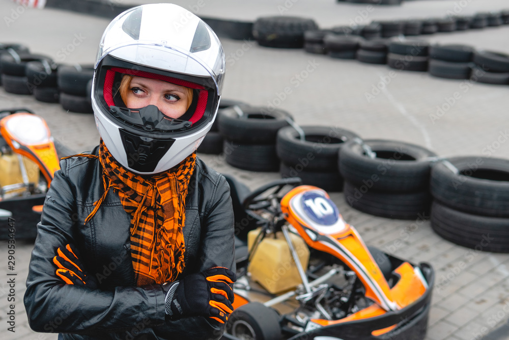 Portrait of a pretty girl wearing a white helmet close up, detail of Go-kart. karting track racing, copy space. serious look, determination, active lifestyle, extreme sport Portrait of a pretty girl wearing a white helmet close up, detail of Go-kart. karting track racing, copy space. serious look, determination, active lifestyle, extreme sport