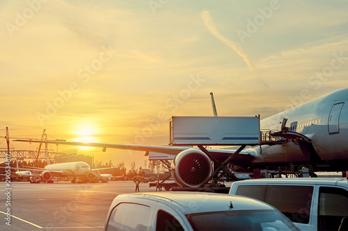 Modern passenger airplane parked to terminal building gate at airside apron of airport with close up airplane parts jet engine wing windows gear tow tractor noon sun view photo