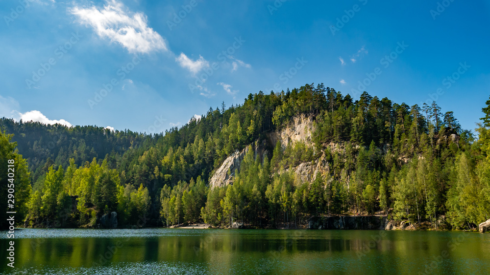 Lake and ancient pines growing between them located in rock city Adrspach, National Park of Adrspach, Czech Republic.