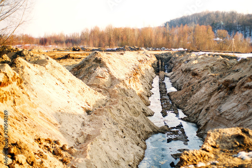 Deep trench dug in the ground to lay pipes. Laying the pipeline late autumn on a sunny day photo