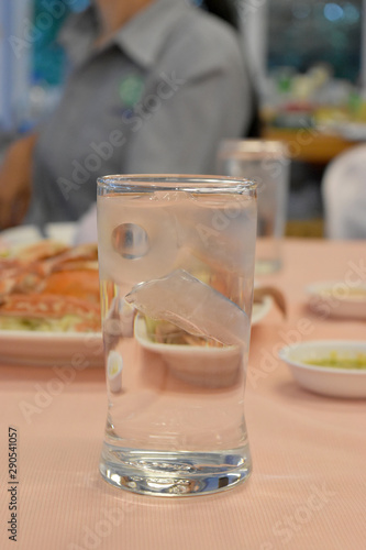 Cool water glass with ice on table.