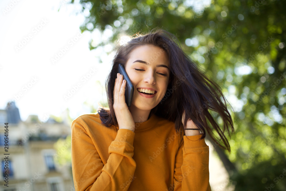 happy young woman laughing while talking with mobile phone happy young woman laughing while talking with mobile phone