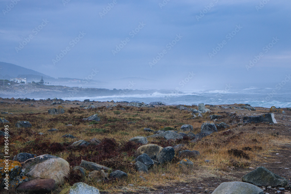Aerial view of road with stones on Atlantic coast. Stones and rocks with moss on road along the ocean. Seacoast with morning mist in perspective. Camino de Santiago landscape. Aerial view of road with stones on Atlantic coast. Stones and rocks with moss on road along the ocean. Seacoast with morning mist in perspective. Camino de Santiago landscape.