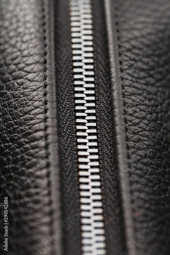 Close-up of the lock on a bag made of genuine black leather, on a dark background