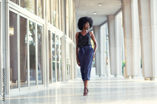 A young fashionable Afro-American woman confidently walking down the hall outside the financial building