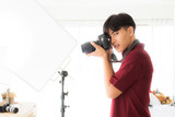young photographer wearing a red shirt Taking photos in a private studio A studio that was done in his house