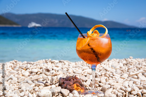 Fototapeta Naklejka Na Ścianę i Meble -  Glass of cold Aperol spritz cocktail on the white pebbles of the amazing Antisamos beach, Kefalonia island, Greece.