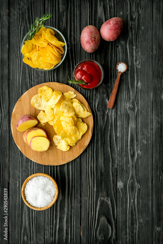 Cooking homemade potato chips with ketchup on wooden background top view