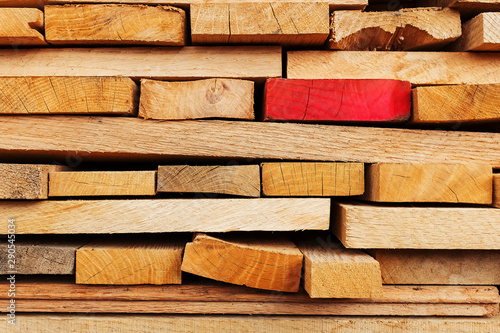 Sawn and folded boards with an emphasis on one red board, construction boards, full-screen lumber as a background.