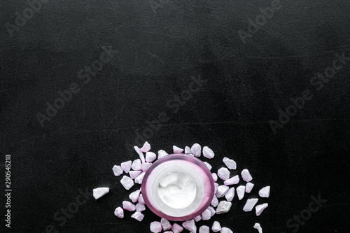 Cosmetics with sea salt decoration on black background top view copyspace