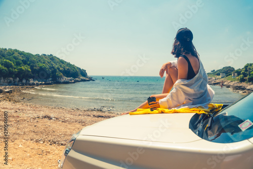 happy woman at sea summer beach sitting at car hood