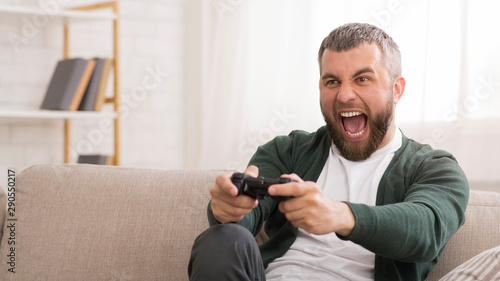 Middle-aged excited man playing video games at home