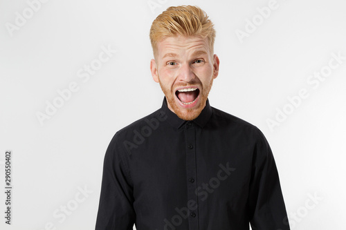 Excited surprised shock young shouting man isolated on gray background. Happy Redhead guy with red beard in black stylish shirt. Success and pass exam concept. Copy space. Close up of Face expression.