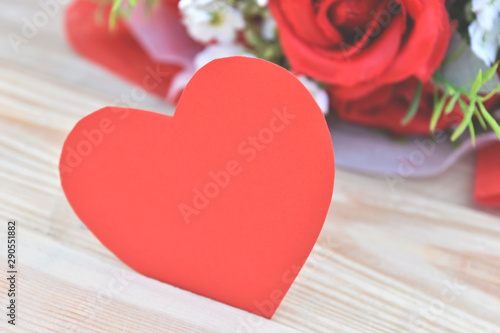 Red roses bouquet and paper hearts shape put on wooden background. Concept for Valentine's day, Birthday or Wedding.