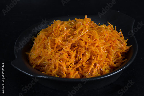 Spicy Korean carrot salad in black plate on black background