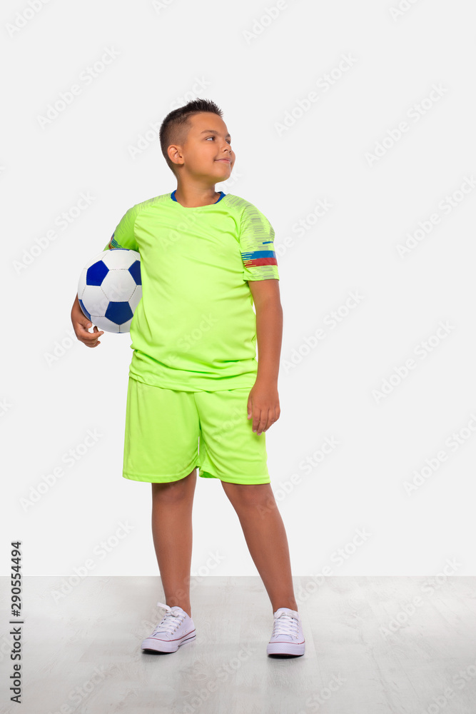 Studio portrait of a positive smiling mixed race boy in green football uniform and with ball, isolated Studio portrait of a positive smiling mixed race boy in green football uniform and with ball, isolated