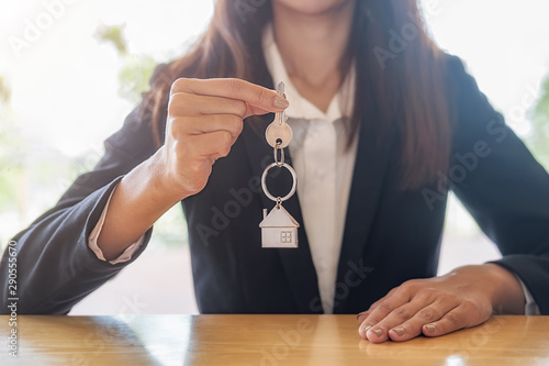 Real estate agent holding a key and asking costumer for contract to buy, get insurance or loan real estate or property background.
