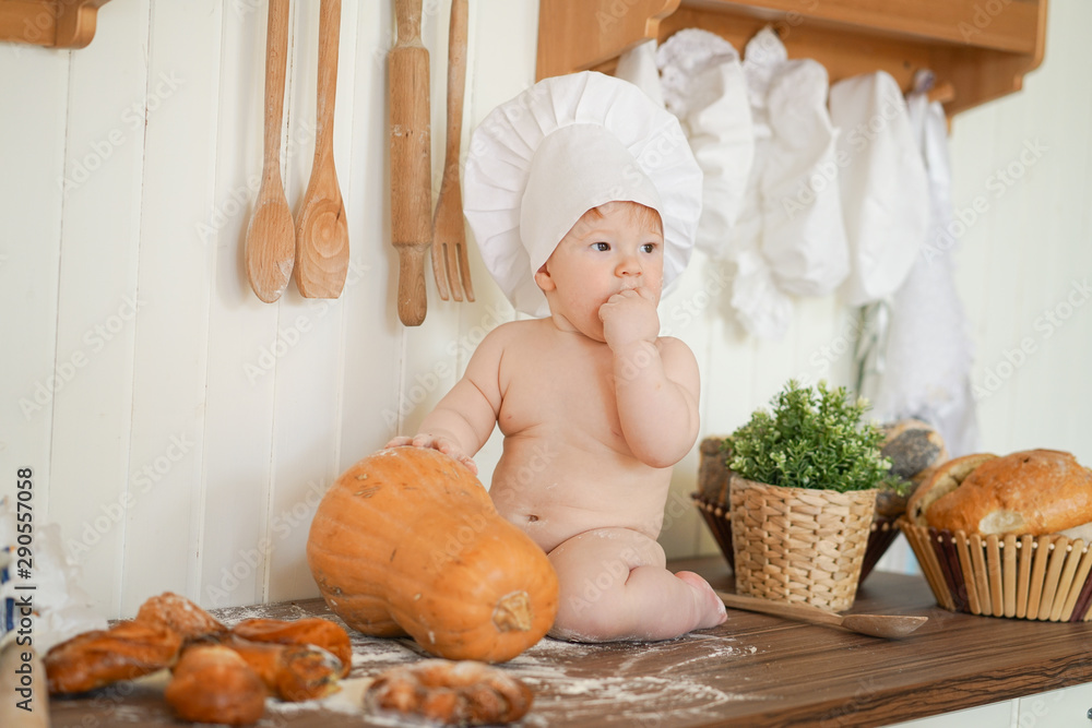 little baker baby child in chef hat at kitchen table alone with orange big pumpkin little baker baby child in chef hat at kitchen table alone with orange big pumpkin