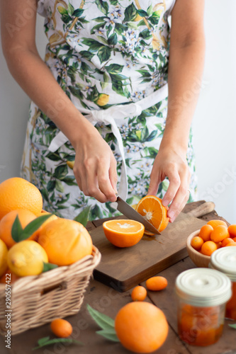 Person with printed kitchen apron cutting an orange