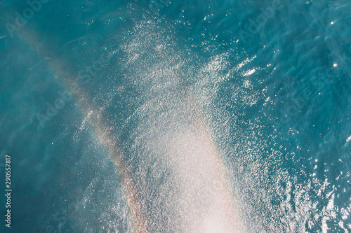 Beach, travel and environment concept. Rainbow on blue ocean background. Ocean water surface texture, vintage summer background.