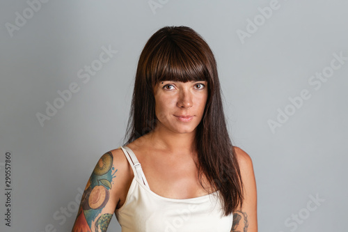 Portrait of a young tanned brunette woman with tattoos. Copy space