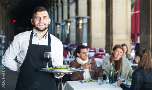 waiter with serving tray welcoming to restaurant
