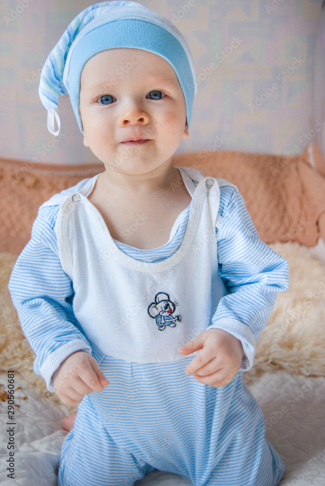 Funny cute baby boy in a gnome hat in a bed