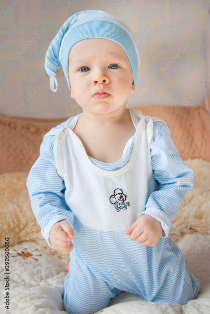 Funny cute baby boy in a gnome hat in a bed