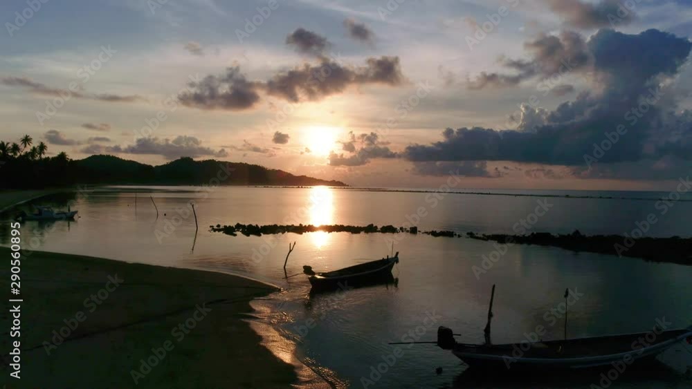 Sunrise over the ocean on a tropical island, boat in the foreground Sunrise over the ocean on a tropical island, boat in the foreground
