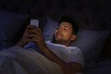 Handsome man using smartphone at night. Bedtime