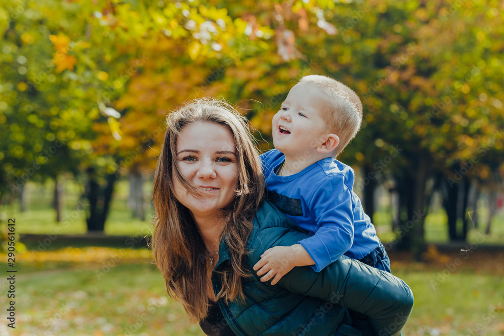 portrait of a beautiful young mother with her son walks in the autumn park. portrait of a beautiful young mother with her son walks in the autumn park.