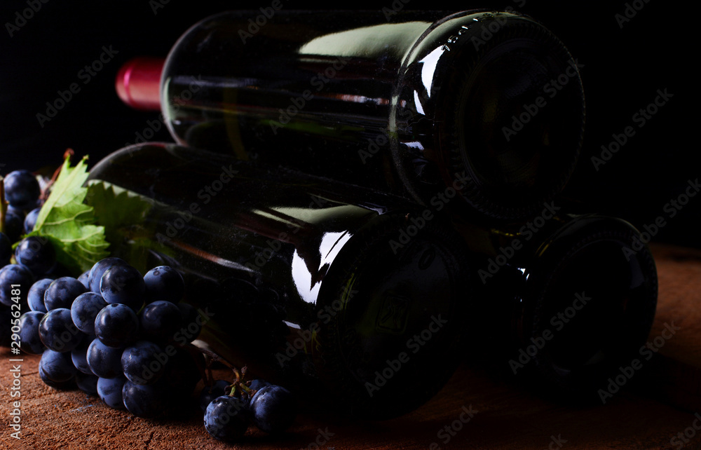 Obraz premium Wine bottles and grapes on a black background