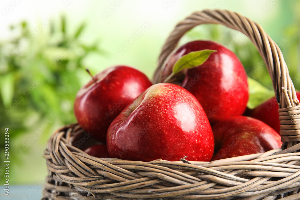 Wicker basket with ripe juicy red apples against blurred background, closeup Wicker basket with ripe juicy red apples against blurred background, closeup