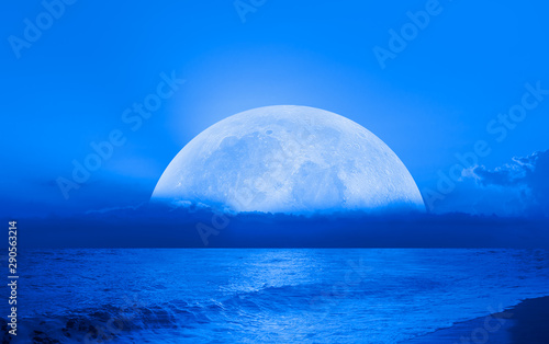 Night sky with moon in the clouds on the foreground blue sea"Elements of this image furnished by NASA