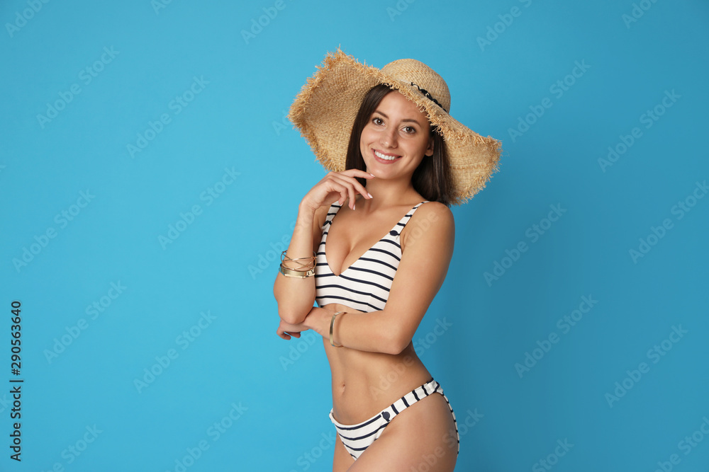 Pretty sexy woman with slim body in stylish striped bikini on blue background. Space for text