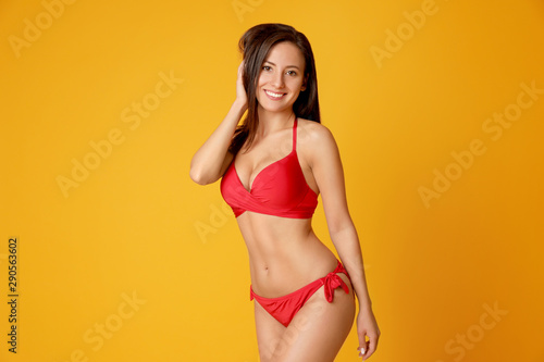 Pretty sexy woman with slim body in stylish red bikini on orange background, space for text