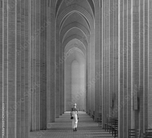 a woman is walking down the long archways of the cathedral photo