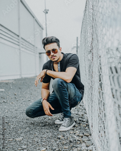 Man crouching next to chainlink fence