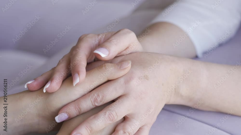 Two women holding hands close-up. Mother calming her daughter. Friendly relationship in family. Generations concept. Two women holding hands close-up. Mother calming her daughter. Friendly relationship in family. Generations concept.