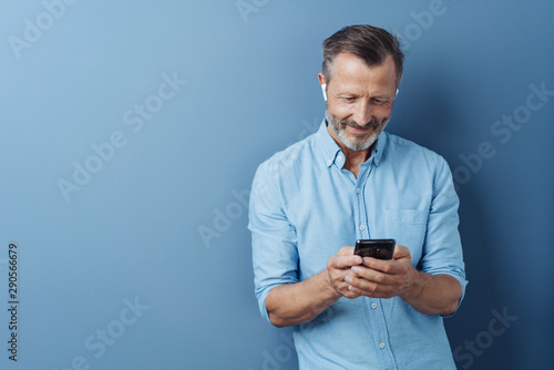 Man wearing audio ear buds holding a mobile phone photo