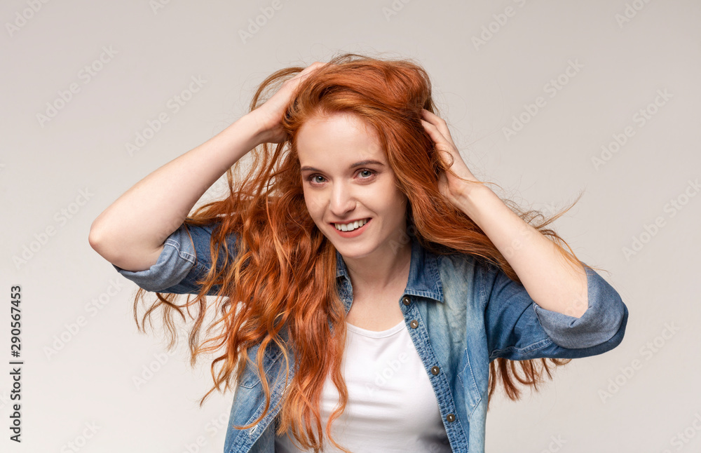 Redhead girl brushing hair with fingers, enjoying her natural look Redhead girl brushing hair with fingers, enjoying her natural look