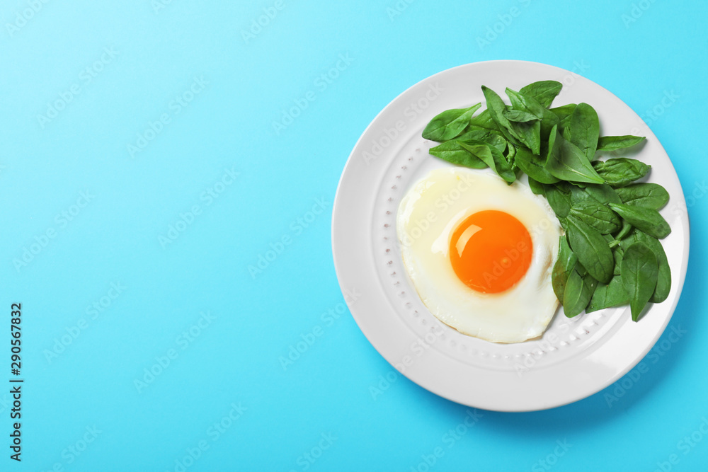 Plate of fried egg and spinach on light blue background, top view with space for text. Healthy breakfast Plate of fried egg and spinach on light blue background, top view with space for text. Healthy breakfast