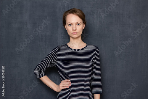 Portrait of serious focused girl holding arm on waist