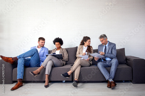 Group of four business people sitting on sofa