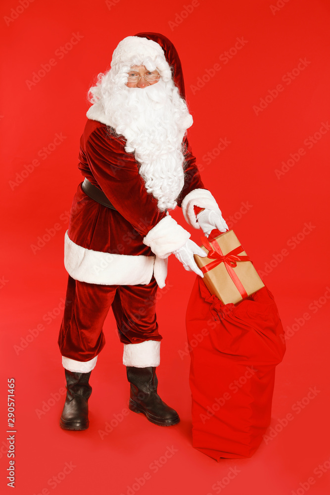 Authentic Santa Claus with sack and gift on red background Authentic Santa Claus with sack and gift on red background