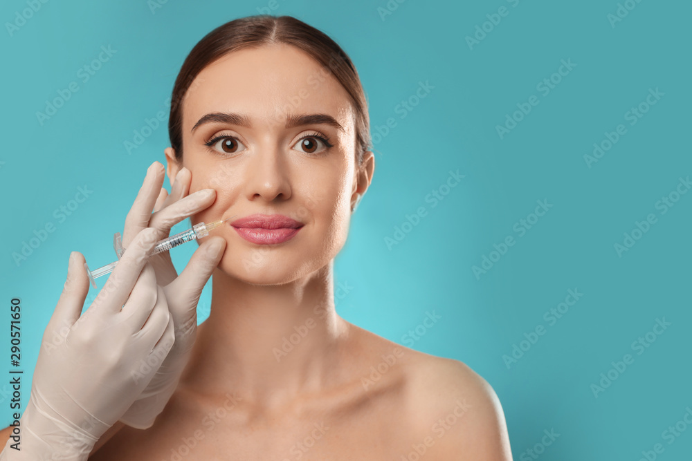 Beautiful woman getting facial injection on light blue background. Cosmetic surgery Beautiful woman getting facial injection on light blue background. Cosmetic surgery