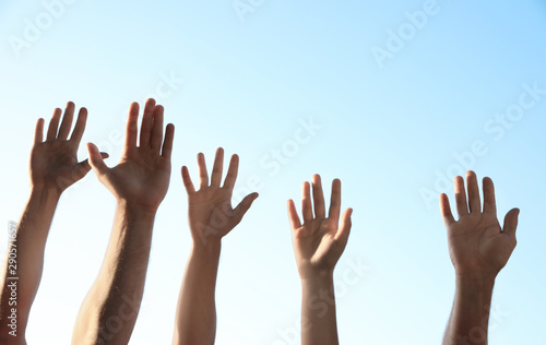 Group of volunteers raising hands outdoors, closeup