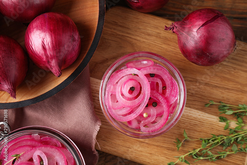 Composition with tasty pickled onions on wooden cutting board, flat lay